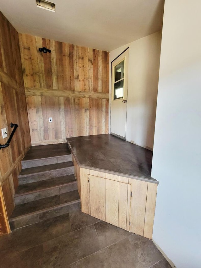 stairway featuring wooden walls