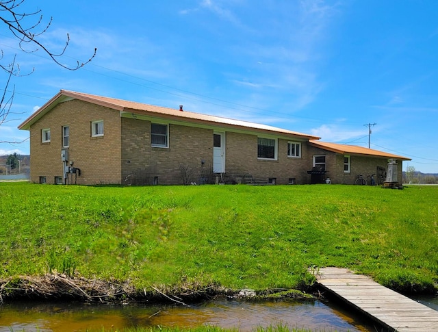 back of property with a lawn and brick siding