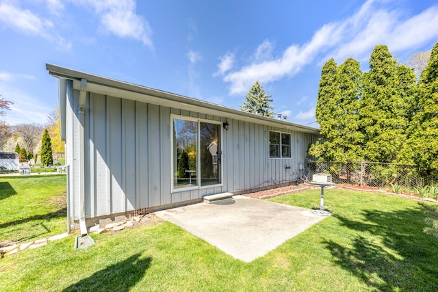 rear view of house with a patio area, board and batten siding, fence, and a yard