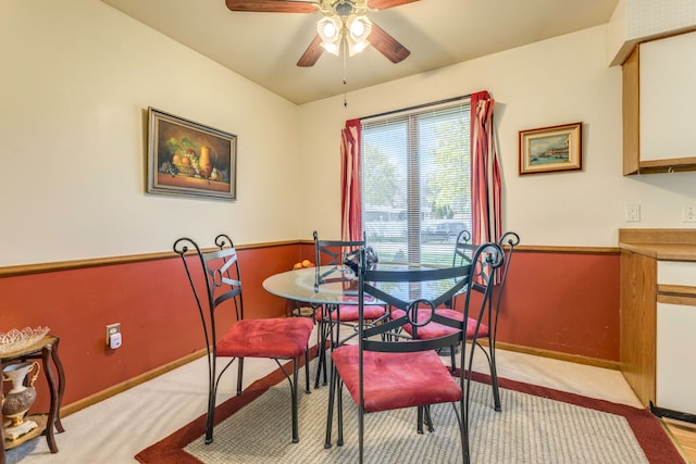 dining area with light colored carpet, a ceiling fan, and baseboards