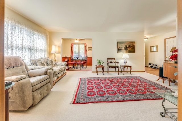 living room with baseboards, a ceiling fan, and carpet