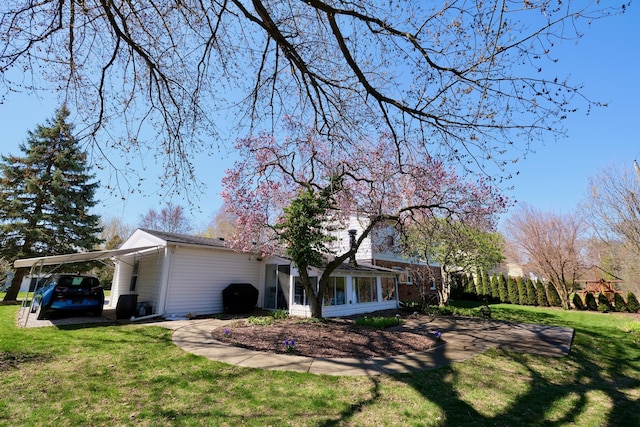 view of side of property featuring a lawn, a sunroom, and an attached carport