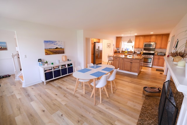 dining room featuring a fireplace, recessed lighting, baseboards, and light wood-style floors