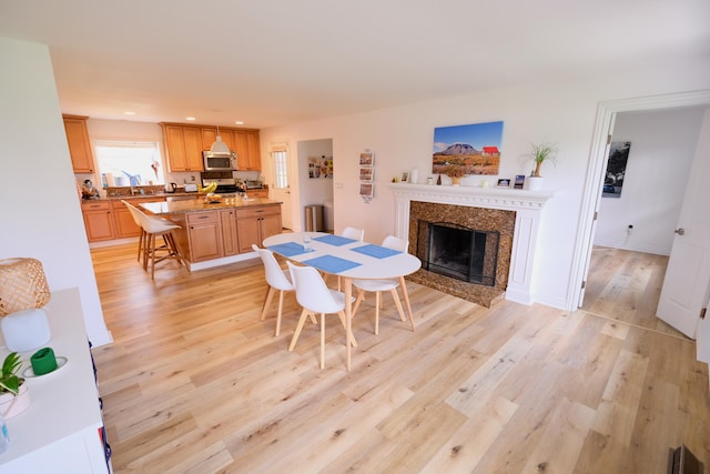 dining space with visible vents, a high end fireplace, light wood finished floors, and recessed lighting