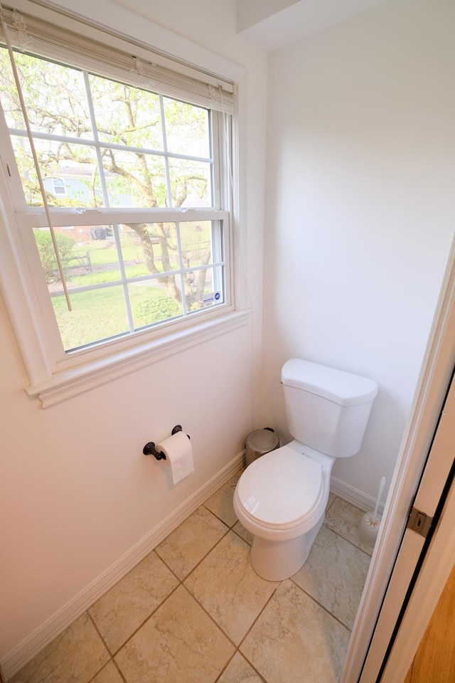 bathroom with baseboards, tile patterned floors, and toilet