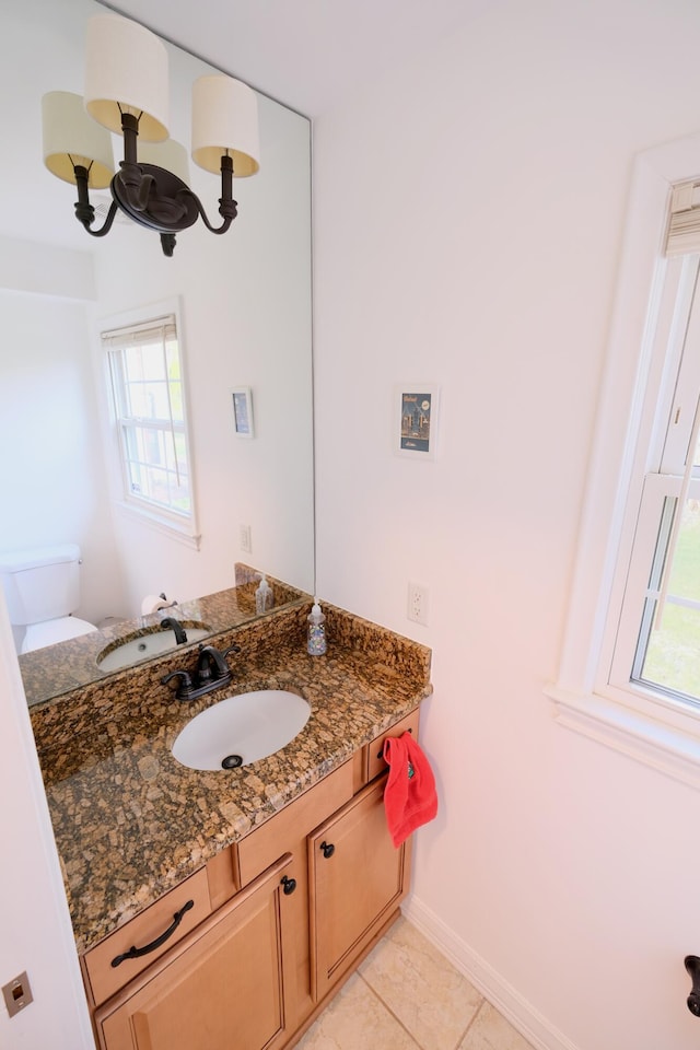 bathroom featuring toilet, baseboards, a healthy amount of sunlight, and vanity