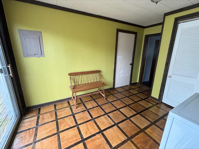 hallway featuring washer / dryer, baseboards, crown molding, and electric panel