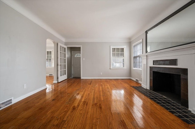 5534 Oldtown St, Detroit, MI 48224 - unfurnished living room featuring visible vents, arched walkways, a tiled fireplace, and wood finished floors