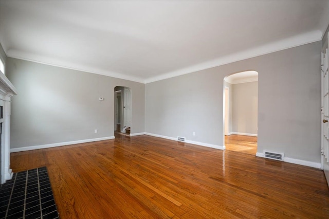 5534 Oldtown St, Detroit, MI 48224 - unfurnished living room featuring arched walkways, a tiled fireplace, wood finished floors, visible vents, and ornamental molding