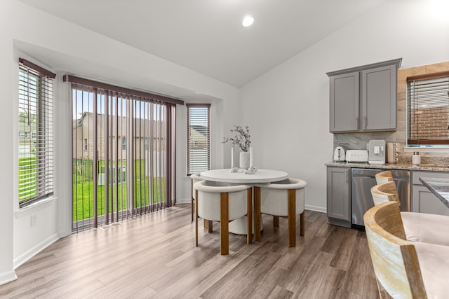 dining room featuring lofted ceiling, baseboards, light wood-style flooring, and recessed lighting