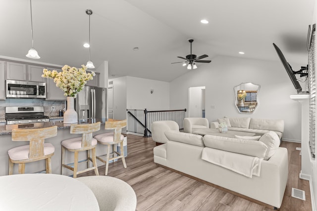living room with ceiling fan, lofted ceiling, and light wood-style flooring