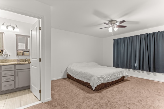 bedroom with baseboards, ceiling fan, visible vents, a sink, and light carpet