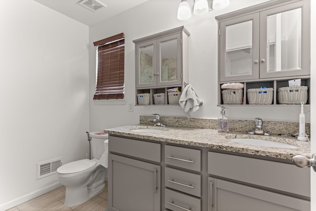 full bath featuring double vanity, toilet, visible vents, and a sink
