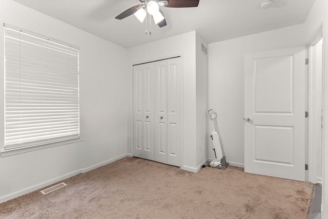unfurnished bedroom featuring baseboards, carpet floors, a closet, and visible vents