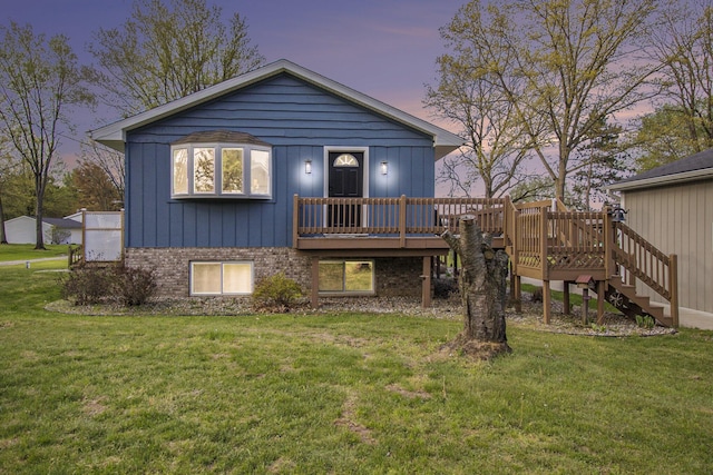 back of house at dusk with brick siding, stairs, a wooden deck, and a yard