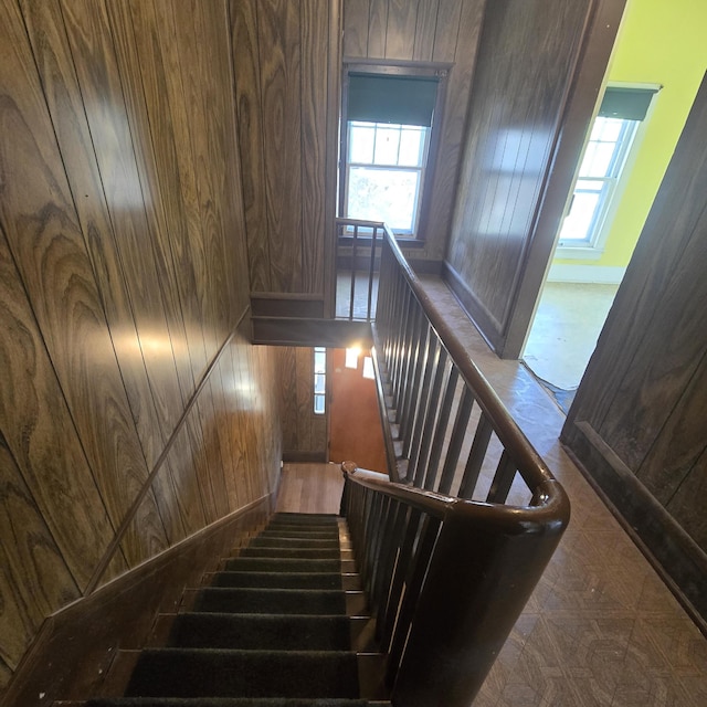 stairway featuring wood walls and plenty of natural light