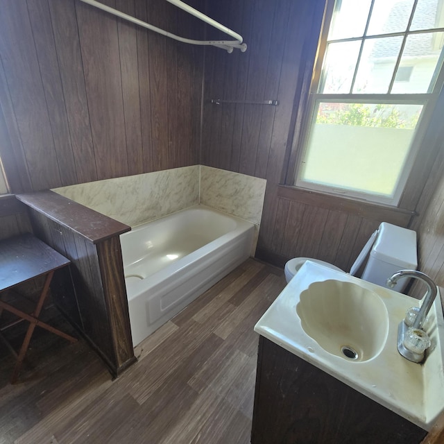 full bathroom featuring wooden walls, vanity, toilet, and wood finished floors