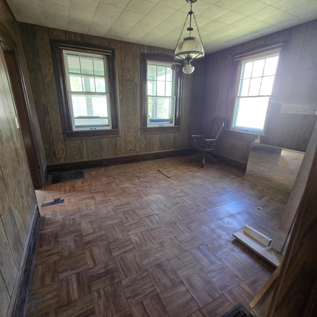 spare room with baseboards, wood walls, and visible vents