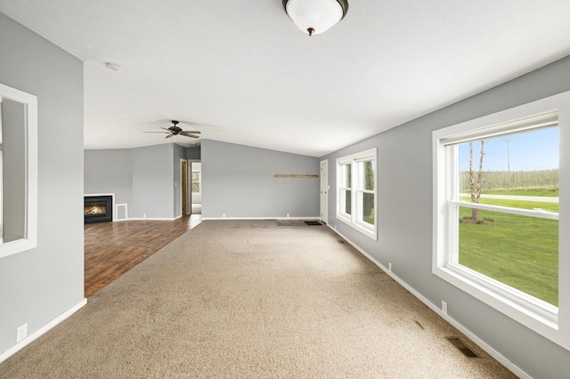 unfurnished living room with baseboards, carpet flooring, lofted ceiling, and visible vents