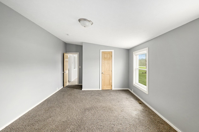 unfurnished bedroom featuring baseboards, carpet, and vaulted ceiling