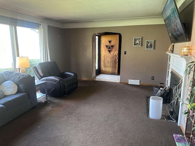 living room with visible vents, arched walkways, a fireplace, baseboards, and carpet flooring