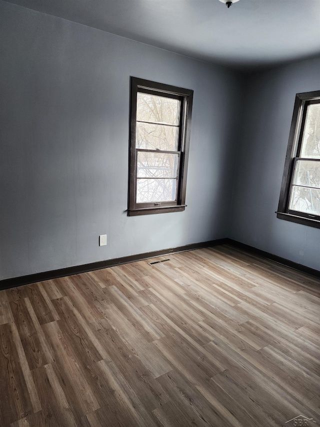 unfurnished room with baseboards and wood finished floors