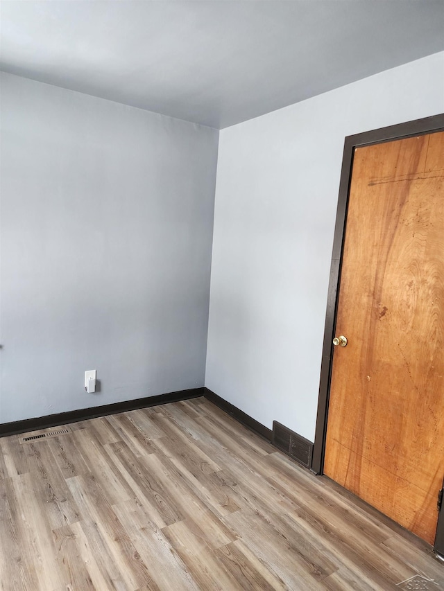 empty room with light wood-type flooring, baseboards, and visible vents