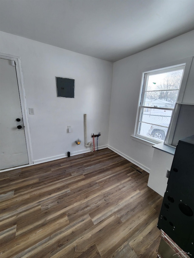 washroom with baseboards, electric panel, laundry area, and dark wood-type flooring