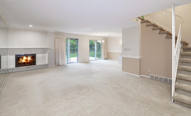 unfurnished living room with visible vents, stairway, crown molding, a fireplace, and carpet flooring