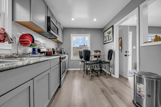 19631 Dwyer St, Detroit, MI 48234 - kitchen with light countertops, tasteful backsplash, a sink, light wood finished floors, and stainless steel appliances