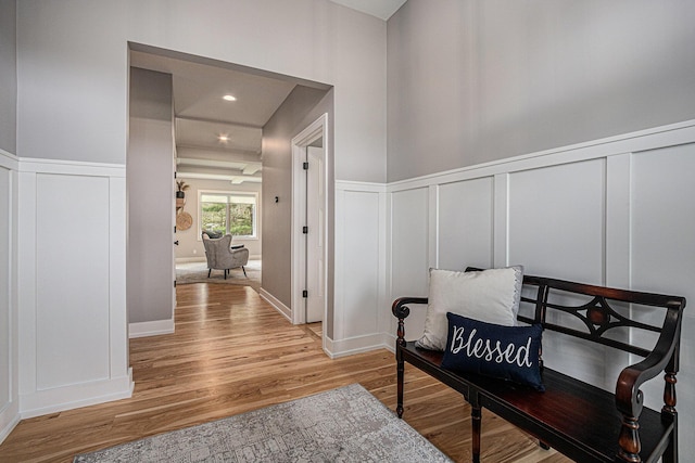 living area featuring wood finished floors, a decorative wall, and a wainscoted wall