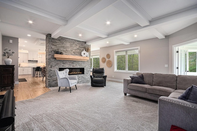 living area with recessed lighting, a stone fireplace, beam ceiling, and plenty of natural light