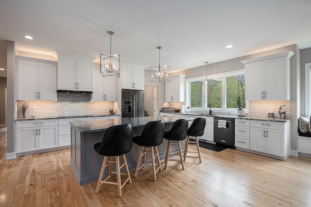 kitchen featuring decorative backsplash, a kitchen breakfast bar, dishwasher, high end fridge, and white cabinetry