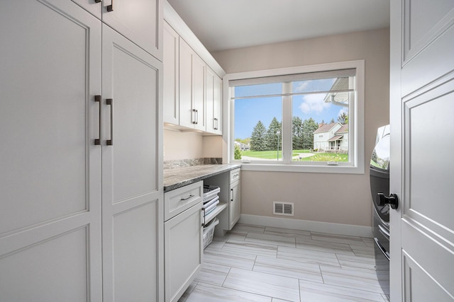 kitchen with visible vents, baseboards, white cabinets, and light stone countertops
