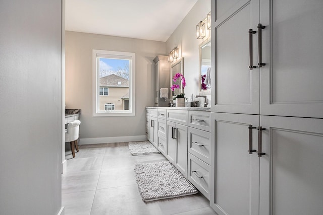full bath with double vanity, baseboards, and tile patterned floors