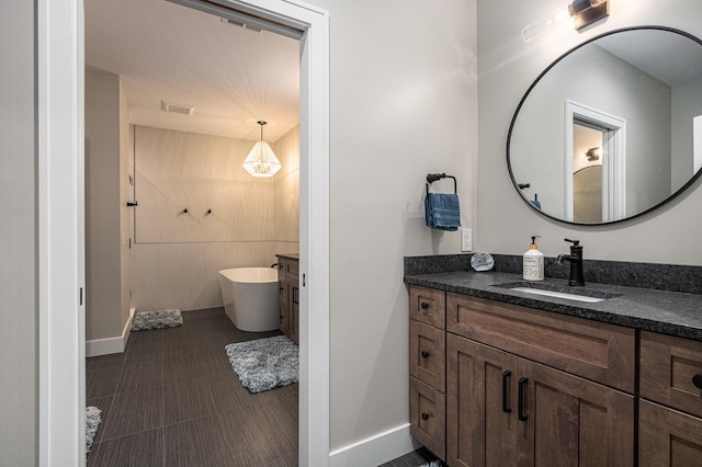 full bath featuring a freestanding tub, visible vents, baseboards, and vanity
