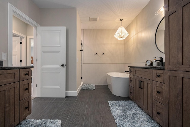 bathroom featuring a freestanding tub, visible vents, tile patterned flooring, and vanity