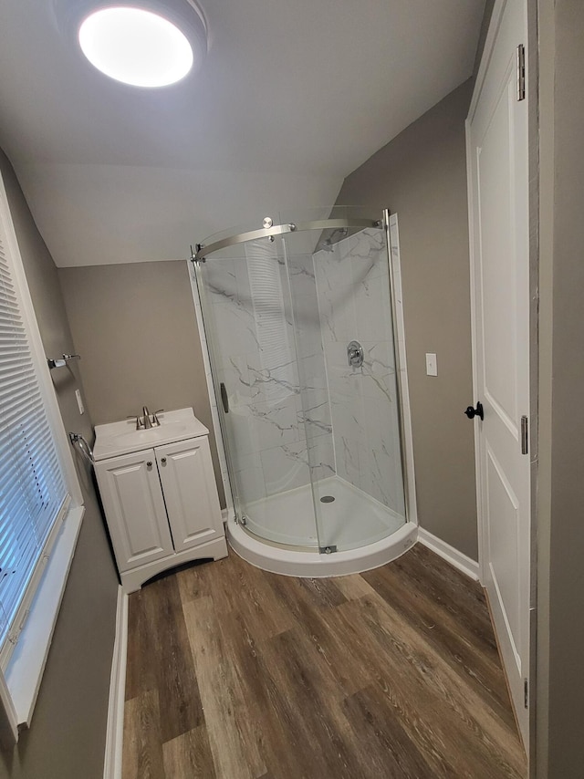 bathroom featuring baseboards, a marble finish shower, wood finished floors, and vaulted ceiling