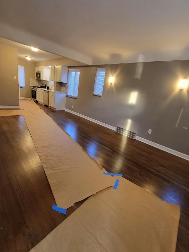 unfurnished living room with baseboards, dark wood finished floors, and visible vents