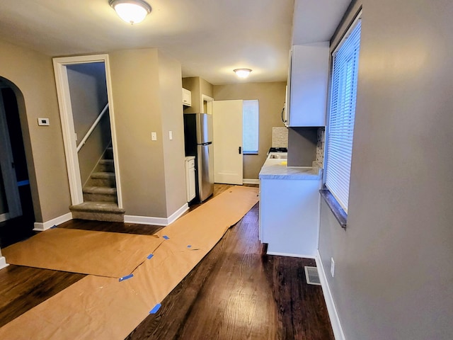 interior space featuring a healthy amount of sunlight, visible vents, arched walkways, wood finished floors, and baseboards