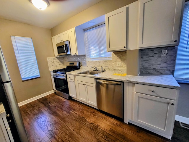 kitchen with a sink, white cabinets, stainless steel appliances, and dark wood-style flooring