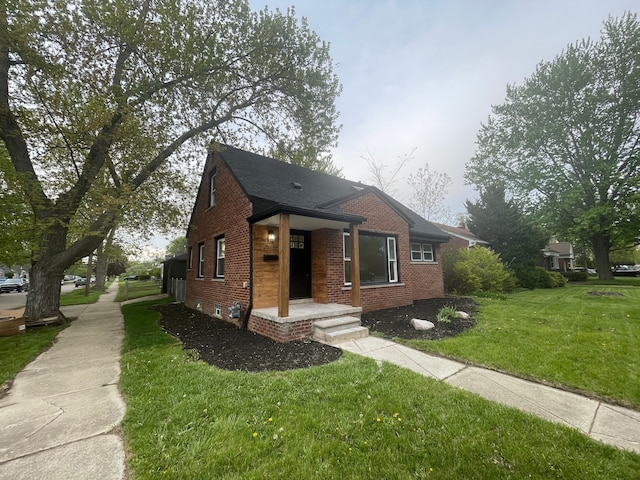 bungalow-style home with a front yard and brick siding