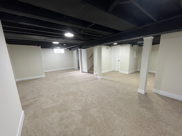 basement with baseboards, light carpet, and stairway