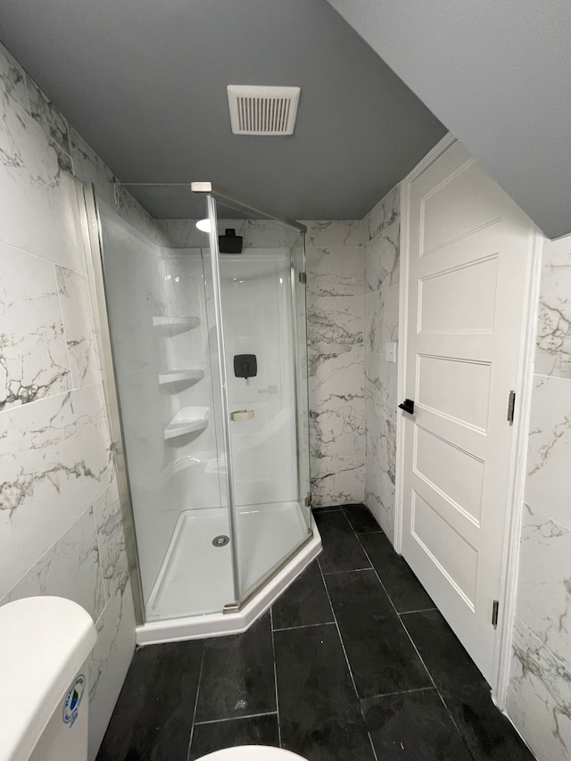 full bathroom featuring visible vents, stone wall, toilet, and a shower stall