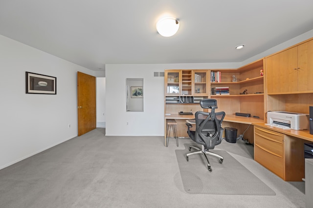 office area with built in study area, baseboards, and light carpet