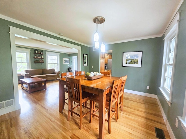 dining space with crown molding, light wood-style floors, and visible vents