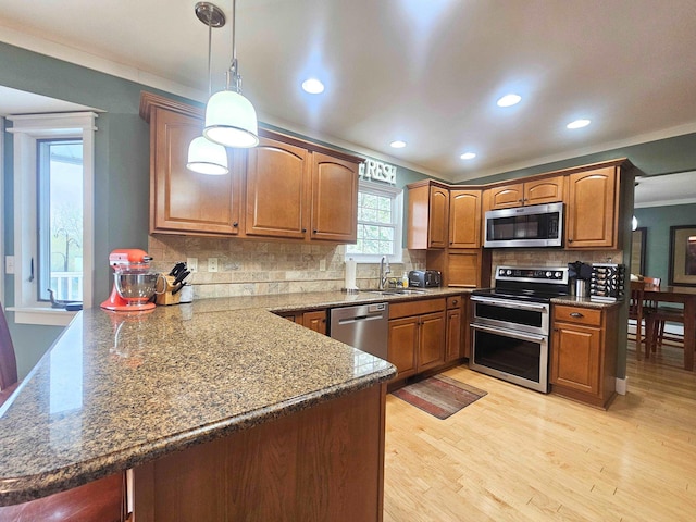 kitchen with ornamental molding, a peninsula, a sink, appliances with stainless steel finishes, and backsplash