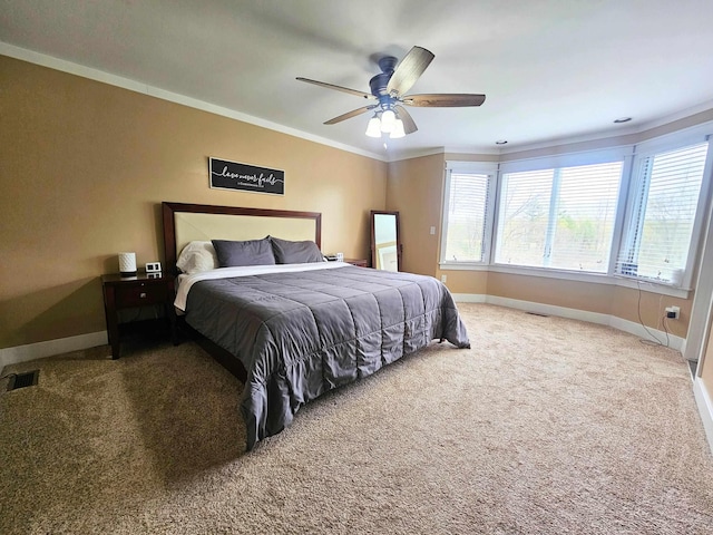 carpeted bedroom with ceiling fan, ornamental molding, baseboards, and visible vents