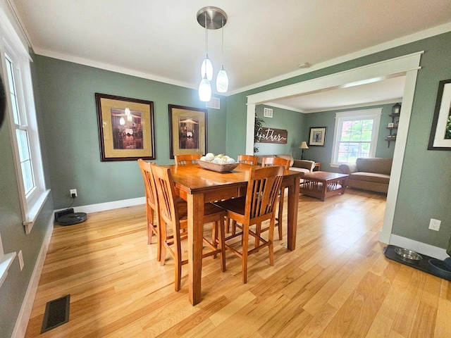 dining room featuring light wood-style floors, baseboards, ornamental molding, and visible vents