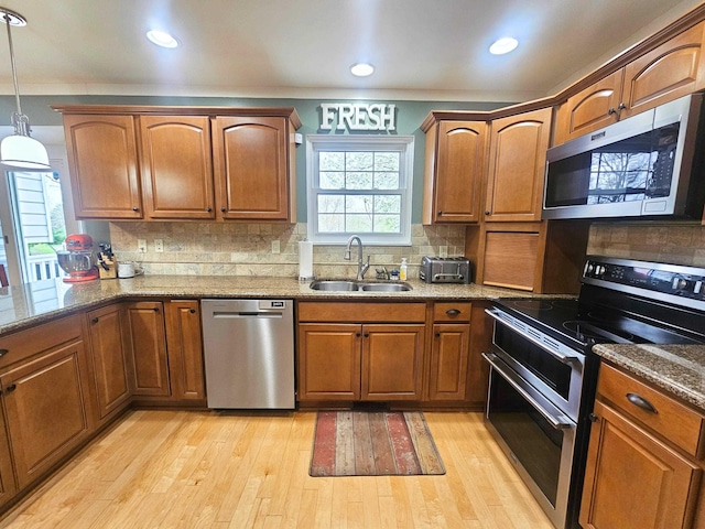 kitchen with light wood-style floors, a sink, brown cabinets, and stainless steel appliances